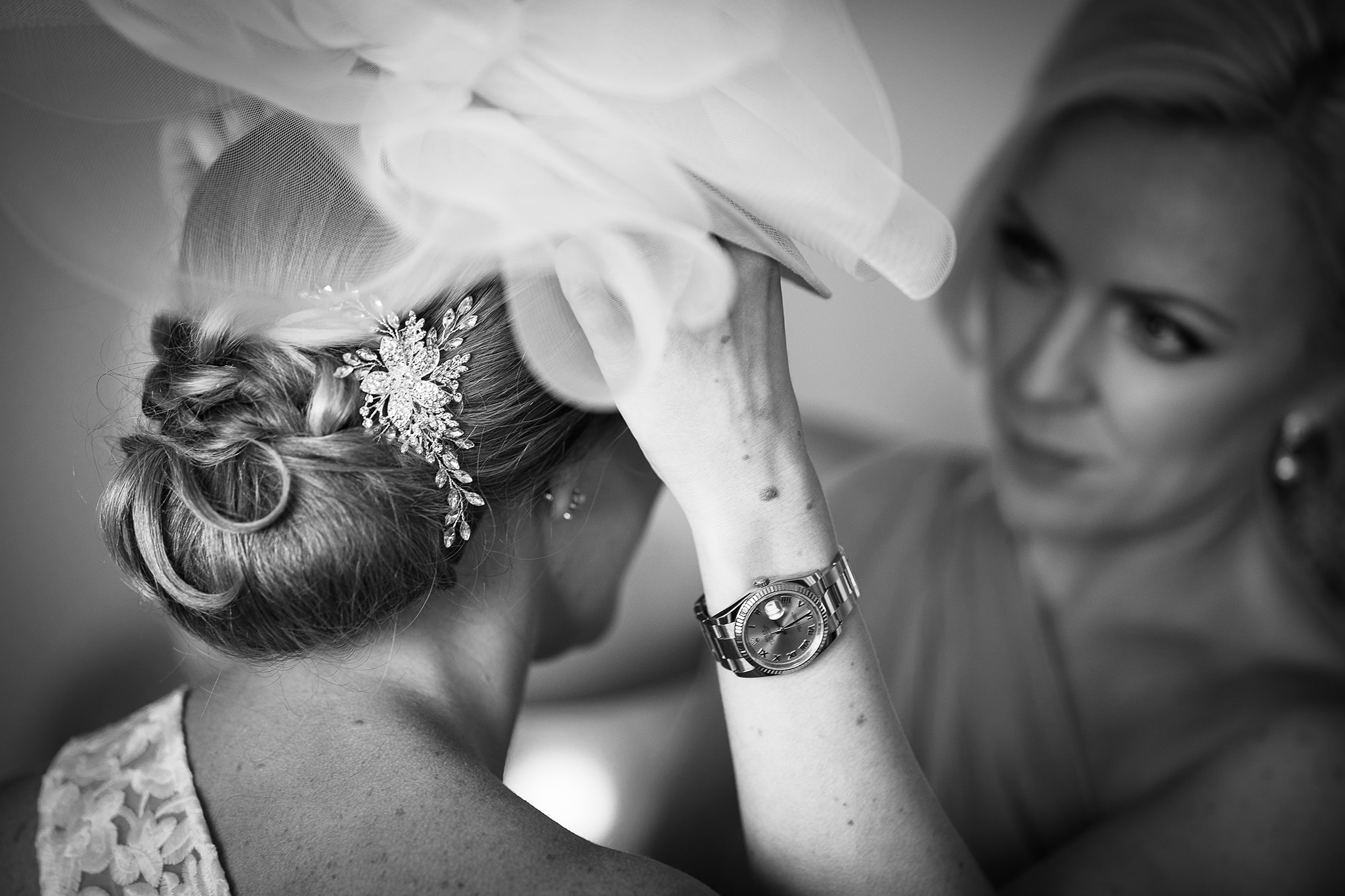 Black and white photo of bride having hat fitted by bridesmaid taken by Hampshire wedding photographer